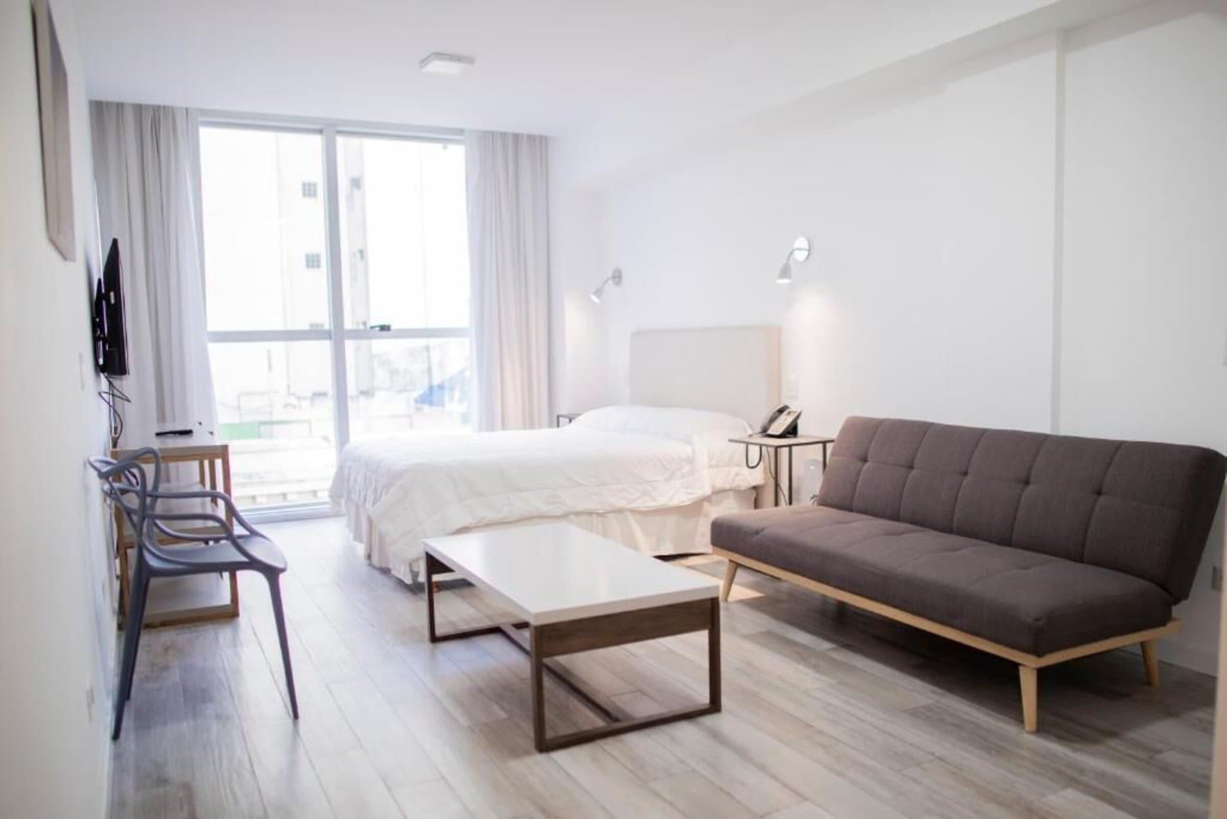 Departamento doble con cama, sofá y ventanal