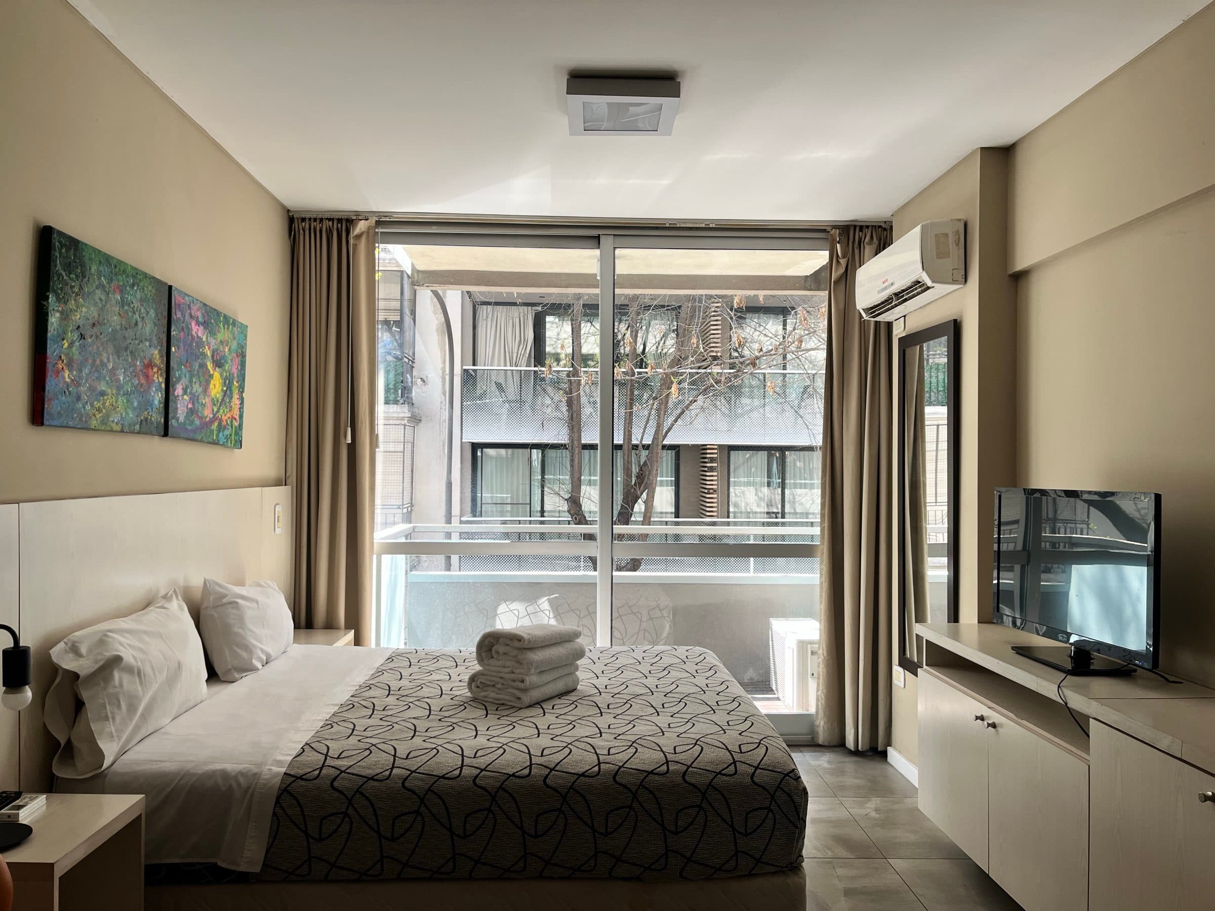 Dormitorio con ventanal y árboles de la calle